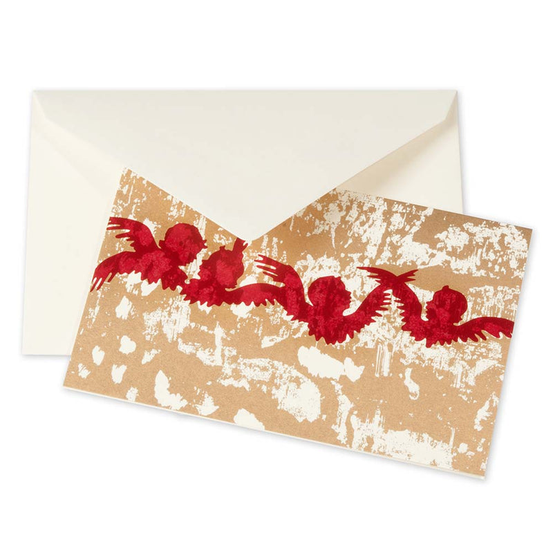 A Christmas card with red silhouettes of flying angels on a rustic golden textured background, paired with a cream envelope.