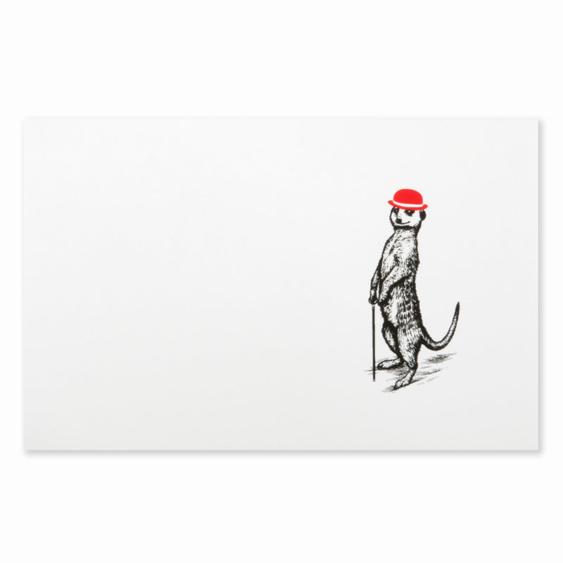 White Christmas card with a black illustration of a meerkat standing upright and holding a cane, wearing a red festive bowler hat.