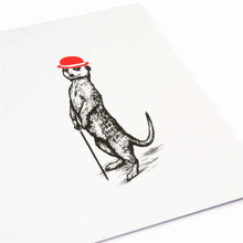 A close-up of a white Christmas card with a black illustration of a meerkat standing upright and holding a cane, wearing a red festive bowler hat.