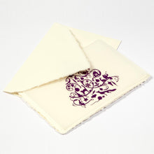 A cream-colored Christmas card with deckle edges, printed with a detailed purple ornamental design featuring festive silhouettes, paired with a cream envelope.