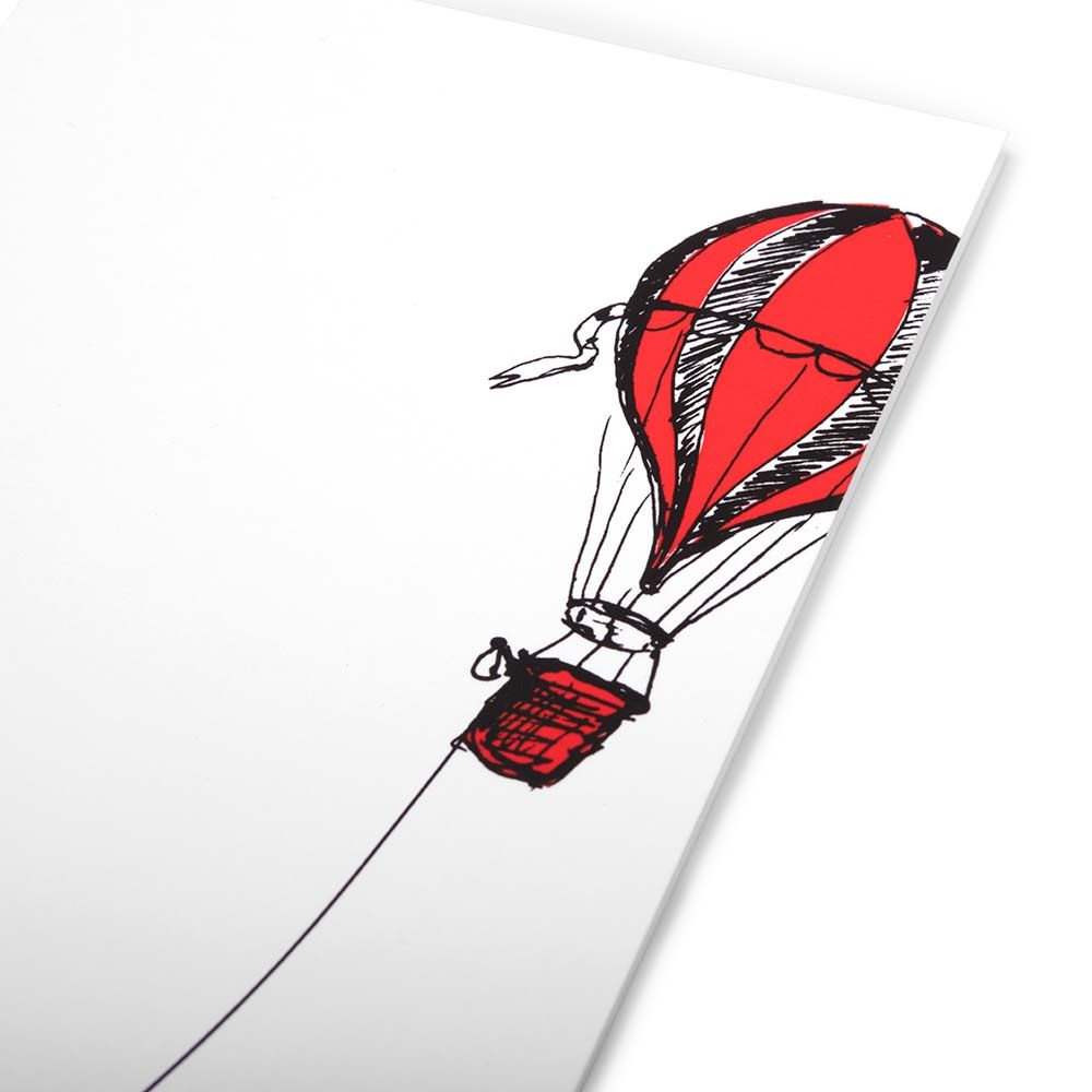A close-up of a minimalist Christmas card with a white background featuring an illustration of a red hot air balloon.