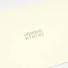 A close-up of a minimalist cream-colored Christmas card with the words 'HOHOHO' in green and 'HIHIHI' in red printed in the center.