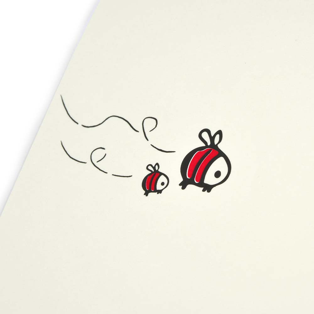 A close-up of a cream Christmas card with two cartoon bees flying on the left.