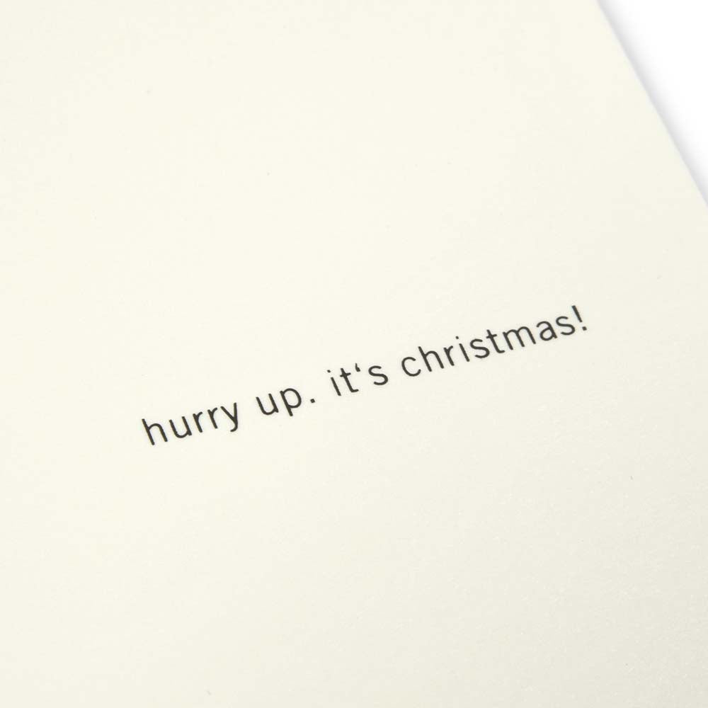 A close-up of a cream Christmas card with the text 'hurry up, it’s Christmas!' on the right.