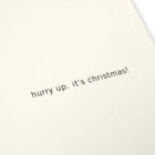 A close-up of a cream Christmas card with the text 'hurry up, it’s Christmas!' on the right.