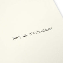 A close-up of a cream Christmas card with the text 'hurry up, it’s Christmas!' on the right.