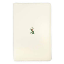 A cream-colored Christmas card with deckled edges, featuring a small holly sprig with green leaves and red berries in the center.