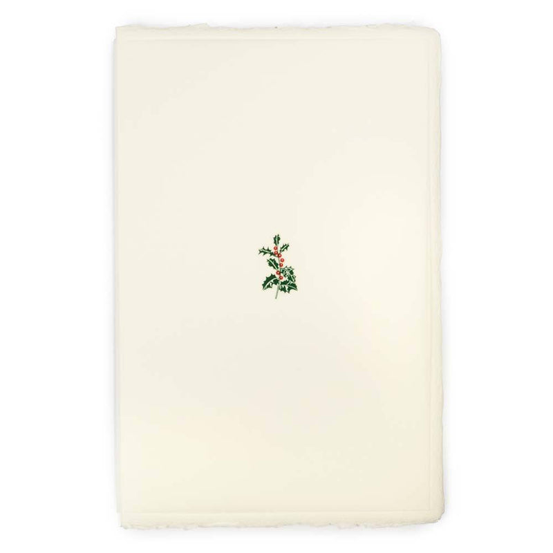 A cream-colored Christmas card with deckled edges, featuring a small holly sprig with green leaves and red berries in the center.