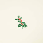 A close-up of a cream-colored Christmas card with deckled edges, featuring a small holly sprig with green leaves and red berries in the center.