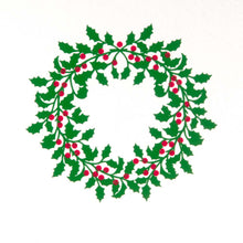 A close-up of a white Christmas card featuring a green holly wreath with red berries.