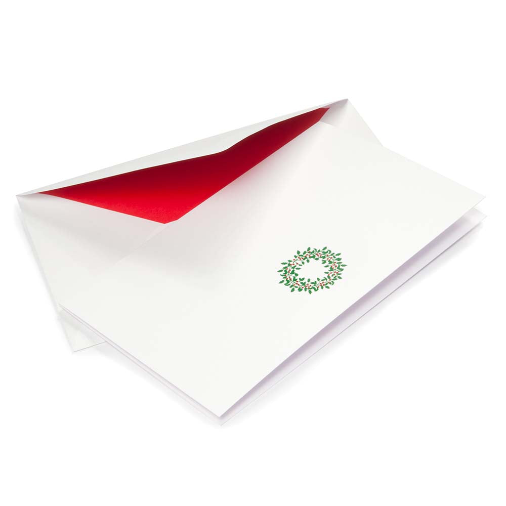 White Christmas card featuring a green holly wreath with red berries, paired with a white envelope lined in bright red.