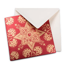 A Christmas card with a decorative golden star and floral pattern on a red background, paired with a cream envelope.