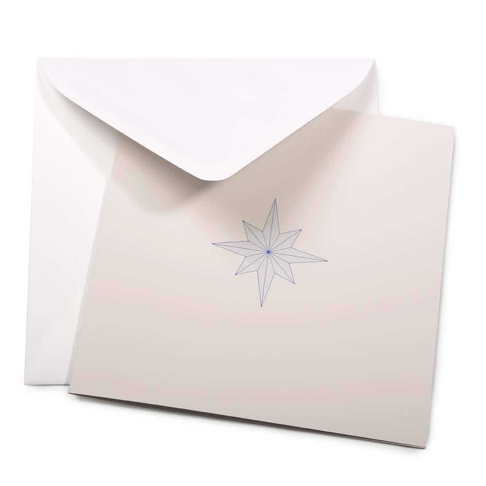 A minimalist Christmas card featuring a fine-lined blue star on a sandy beige background, paired with a white envelope.