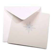 A minimalist Christmas card featuring a fine-lined blue star on a sandy beige background, paired with a white envelope.