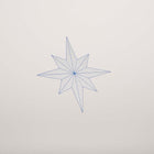 A close-up of a minimalist Christmas card featuring a fine-lined blue star on a sandy beige background.