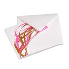 A bright and abstract design with neon pink and gold lametta-style ribbons across the card, with text that reads "Merry Christmas & Happy New Year" in various languages, paired with a white envelope.