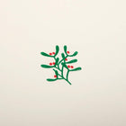 A close-up of a cream-colored Christmas card with a small mistletoe sprig of green leaves and red berries in the center.