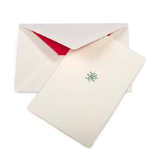 A cream-colored Christmas card with a small mistletoe sprig of green leaves and red berries in the center, shown with a cream envelope lined in bright red.