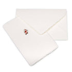 A cream-colored Christmas card with deckled edges, featuring a small illustration of Santa Claus in a red suit holding a sack of gifts, shown with a matching cream envelope.