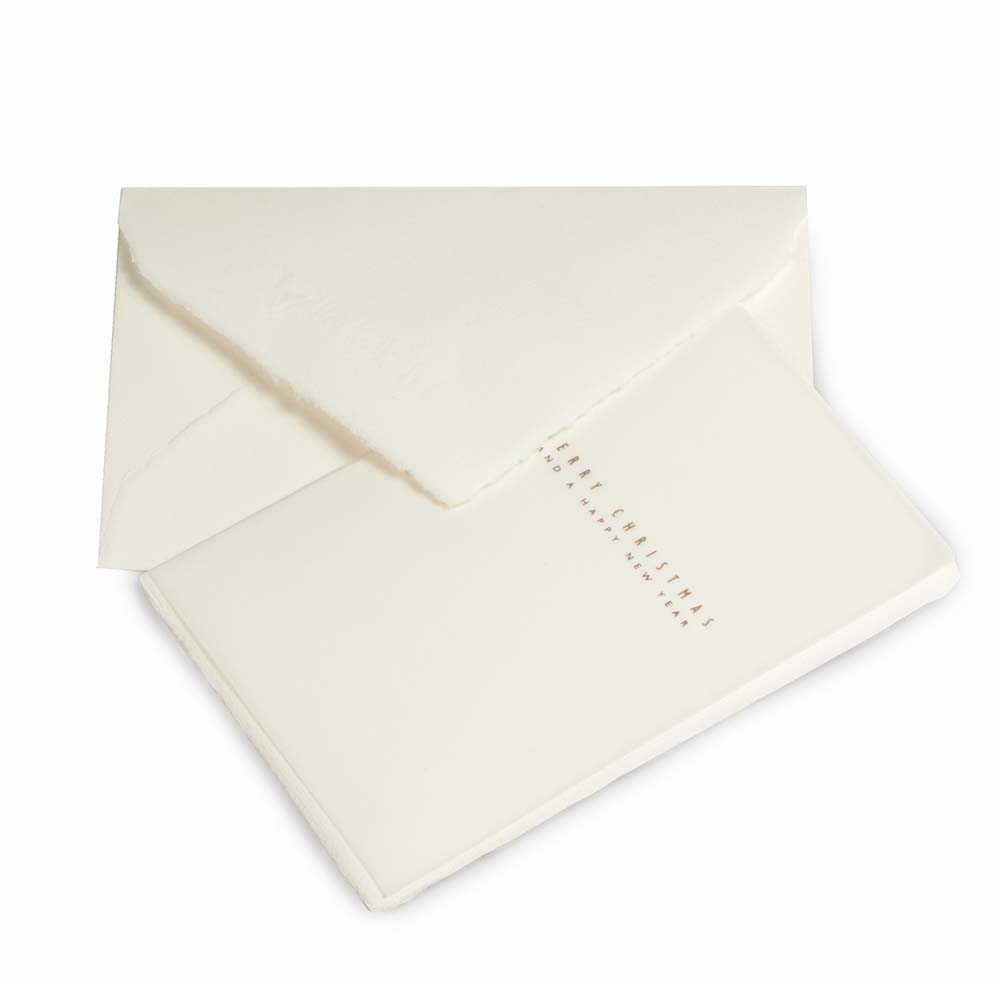Minimalist Christmas card made from textured cream deckle-edged paper, featuring delicate gold lettering that reads “Merry Christmas and Happy New Year,” paired with a matching cream envelope.