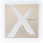 Christmas card with a bold white brushstroke “X” on a gold background and the text “merry x-mas” in small green letters.