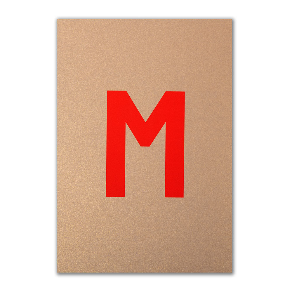 Christmas card with a metallic gold background and a large red letter “M” in the center.