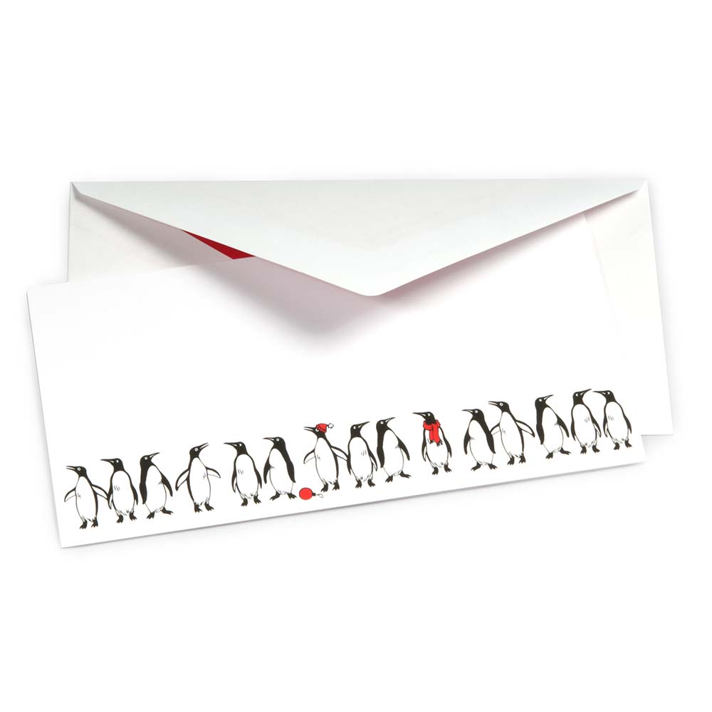 White Christmas card decorated with a row of hand-drawn black and white penguins, some wearing red accessories like a scarf, hat, or holding a ball. Includes a white envelope with a red lining.