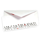 White Christmas card decorated with a row of hand-drawn black and white penguins, some wearing red accessories like a scarf, hat, or holding a ball. Includes a white envelope with a red lining.