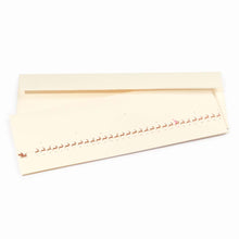 Minimalist cream-colored Christmas card showing a row of small gold reindeer pulling a sleigh, numbered up to 31. The reindeer on the 24th is marked in red. Paired with a matching cream envelope.