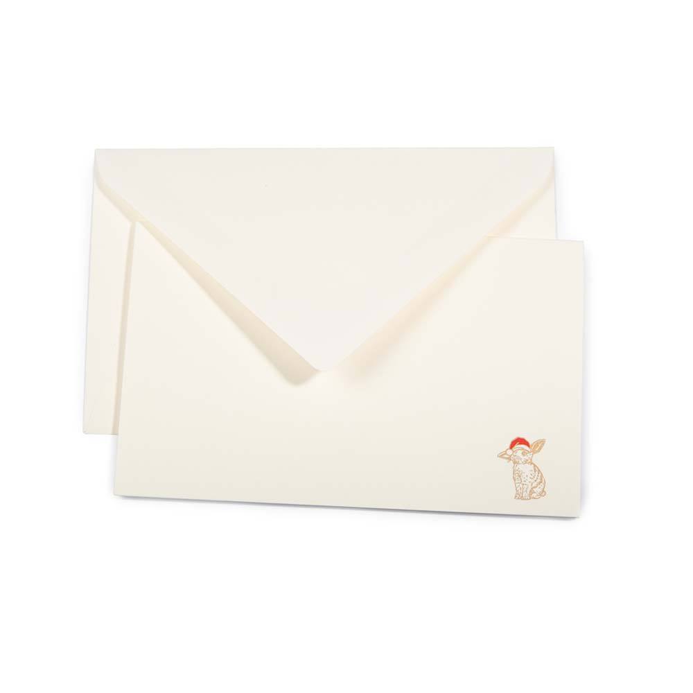 Minimalist cream-colored Christmas card with a small illustration of a rabbit wearing a Santa hat in the bottom right corner, paired with a matching cream envelope.