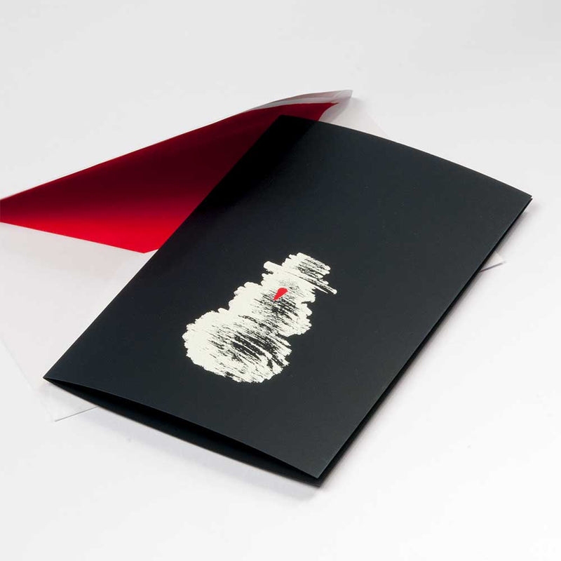 A black Christmas card featuring a rough white sketch of a snowman with a small red carrot nose, paired with a white envelope lined in red.