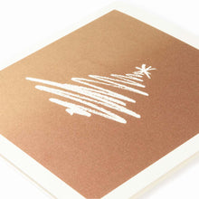 A close-up of a Christmas card on bronze paper with a stylized scribble drawing of a white Christmas tree.