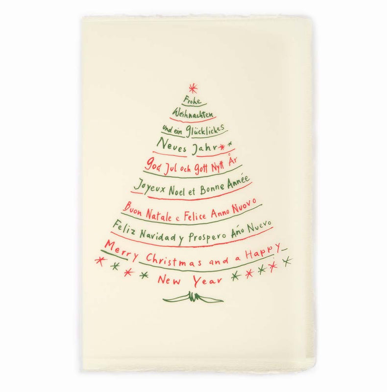 A cream-colored Christmas card with deckled edges, featuring festive greetings in multiple languages written in red and green text arranged in the shape of a Christmas tree.