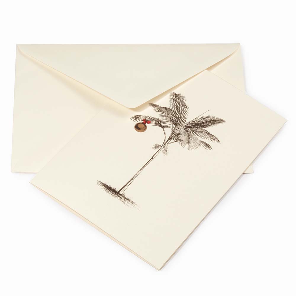 Tropical-themed cream Christmas card featuring a finely sketched palm tree with a single gold ornament hanging from its fronds, paired with a cream envelope.