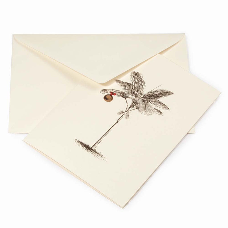Tropical-themed cream Christmas card featuring a finely sketched palm tree with a single gold ornament hanging from its fronds, paired with a cream envelope.
