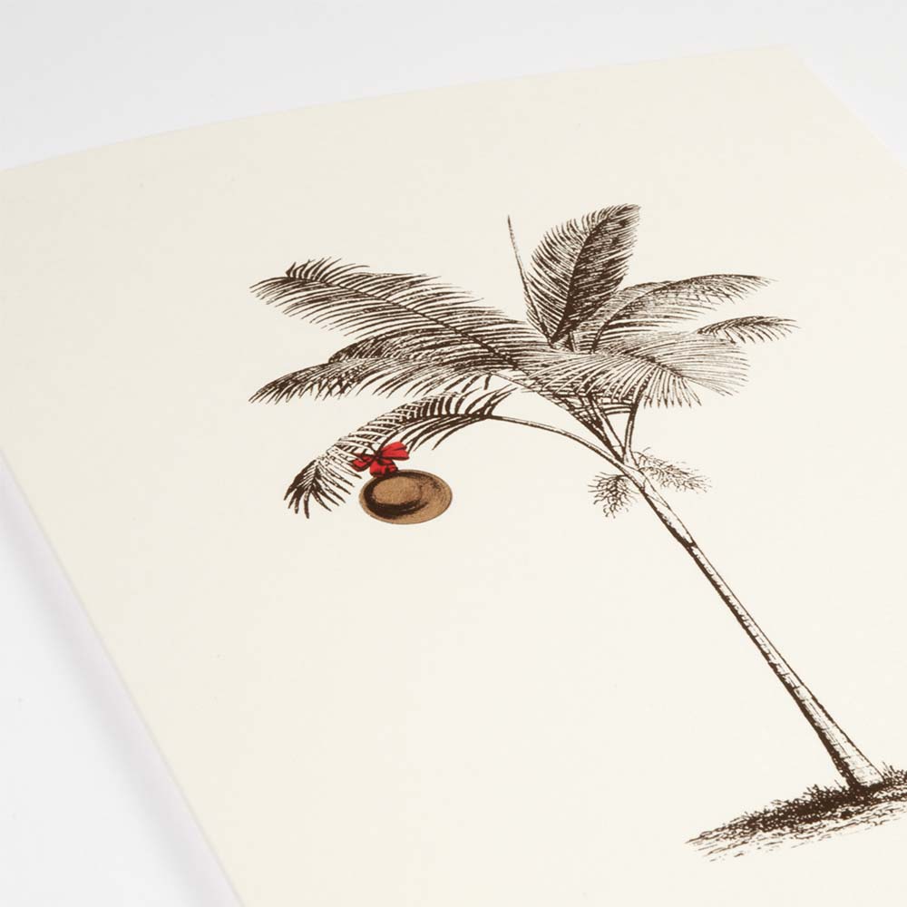A close-up of a tropical-themed cream Christmas card featuring a finely sketched palm tree with a single gold ornament hanging from its fronds.