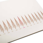 A close-up of a long, slim Christmas card with a row of stylized gold Christmas trees, numbered like a calendar up to 31. The tree on the 24th is highlighted in red.