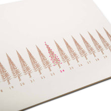 A close-up of a long, slim Christmas card with a row of stylized gold Christmas trees, numbered like a calendar up to 31. The tree on the 24th is highlighted in red.