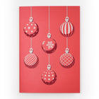 A red Christmas card featuring six hanging ornaments in white and red with various patterns including stripes, snowflakes, and polka dots.